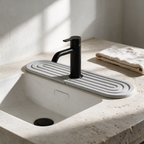 Grey diatomite faucet mat around a black basin tap