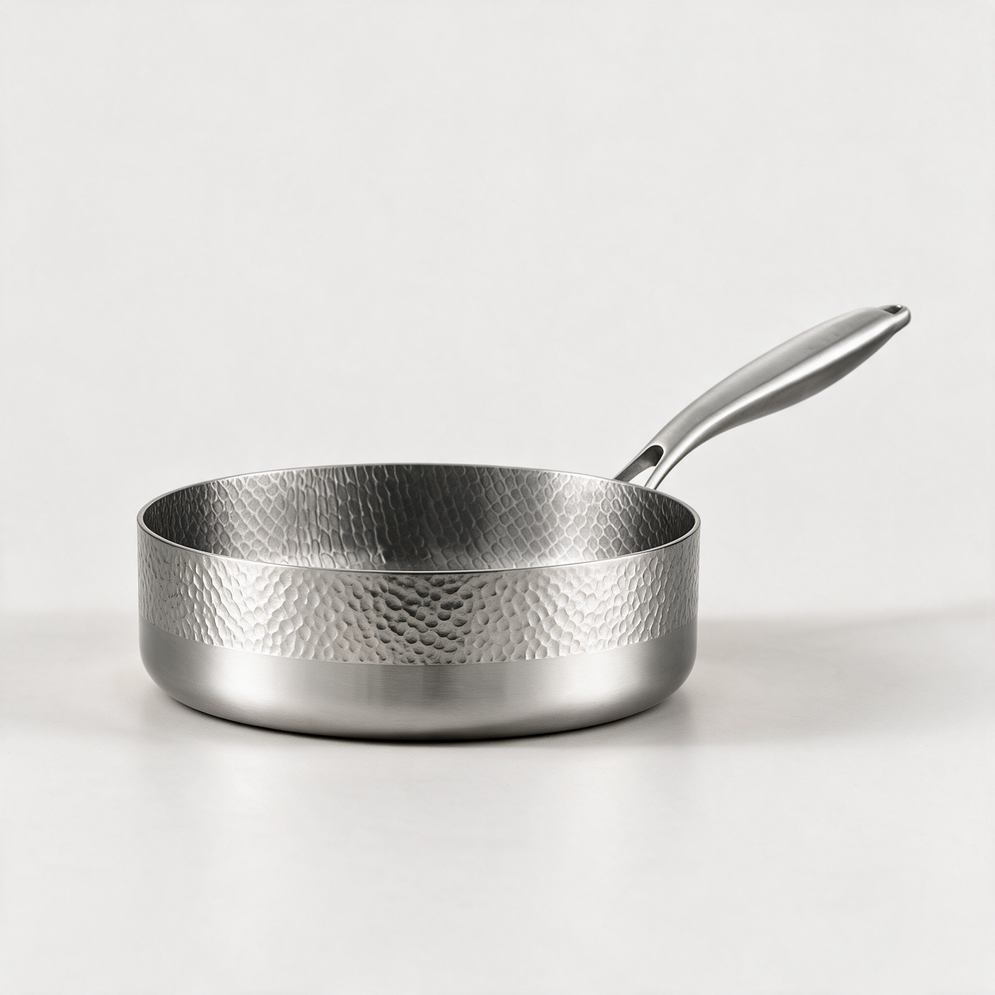 Hammered stainless steel frying pan on a stone worktop