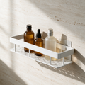 White wall-mounted rectangular bathroom shelf holding glass bottles