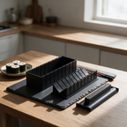 Black sushi and rice mould set on a slate board with finished maki rolls