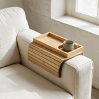 Bamboo sofa arm tray holding a mug, draped over the arm of a linen sofa